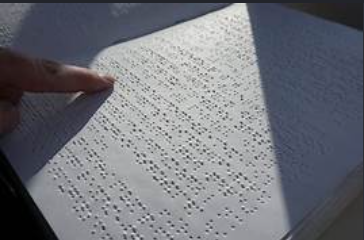 A hand reading a page of Braille